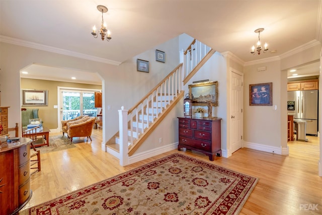 foyer with stairway, light wood-style floors, a chandelier, and ornamental molding