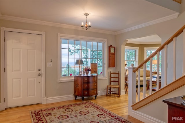 entryway with stairway, arched walkways, ornamental molding, and light wood finished floors