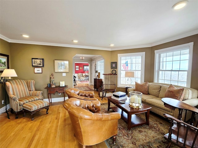 living area with baseboards, arched walkways, light wood-style flooring, and ornamental molding