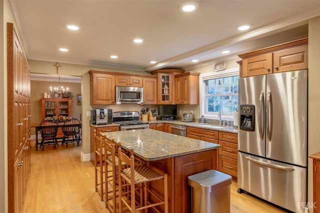 kitchen featuring crown molding, light wood-type flooring, appliances with stainless steel finishes, and a sink