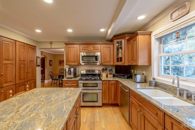 kitchen featuring a sink, brown cabinets, appliances with stainless steel finishes, and light stone countertops