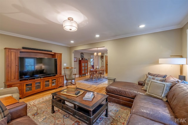 living room featuring a notable chandelier, recessed lighting, light wood-type flooring, and ornamental molding