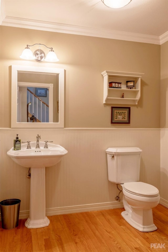 bathroom featuring crown molding, toilet, wood finished floors, and wainscoting