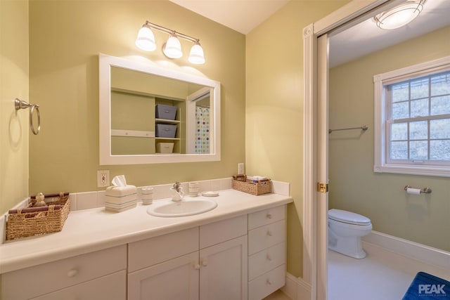 full bath featuring toilet, vanity, and baseboards