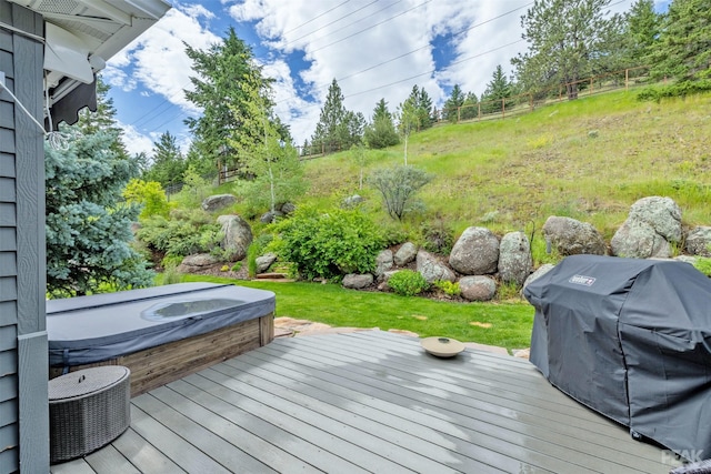 wooden deck with a covered hot tub and a grill