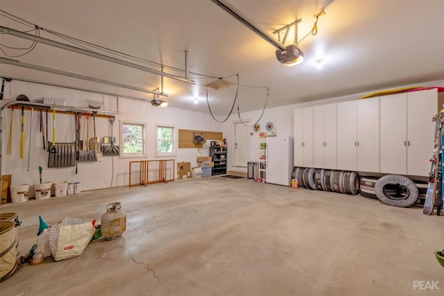 garage with a garage door opener and freestanding refrigerator