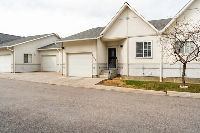 view of front of home with a garage, stucco siding, driveway, and a shingled roof