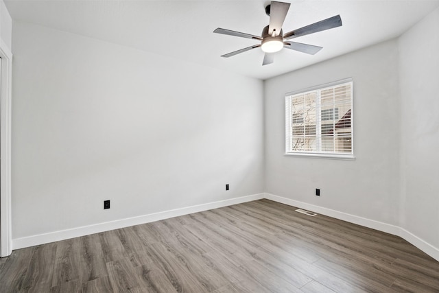 empty room featuring a ceiling fan, wood finished floors, baseboards, and visible vents