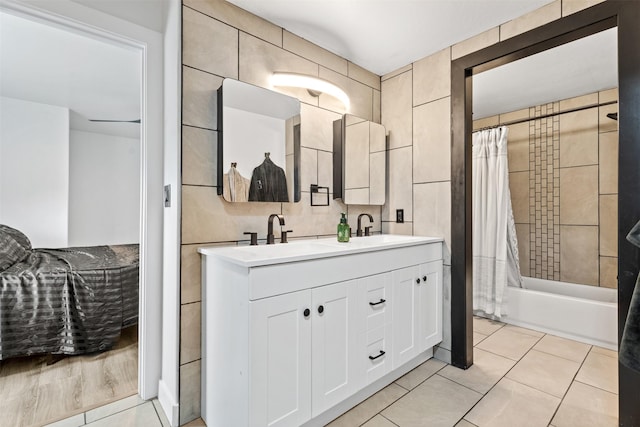 full bath with tile patterned floors, tile walls, shower / tub combo with curtain, and a sink