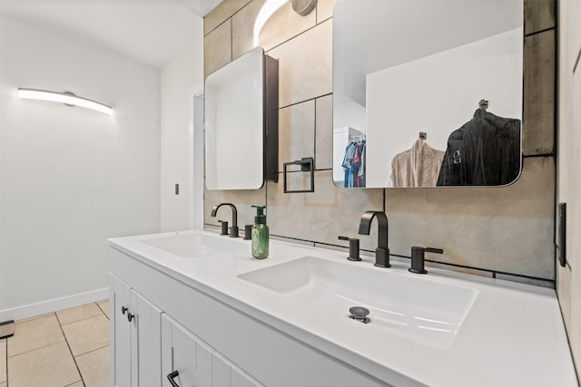 full bath with a sink, baseboards, double vanity, and tile patterned flooring