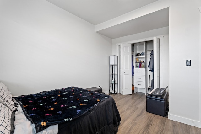 bedroom with a closet, baseboards, and wood finished floors