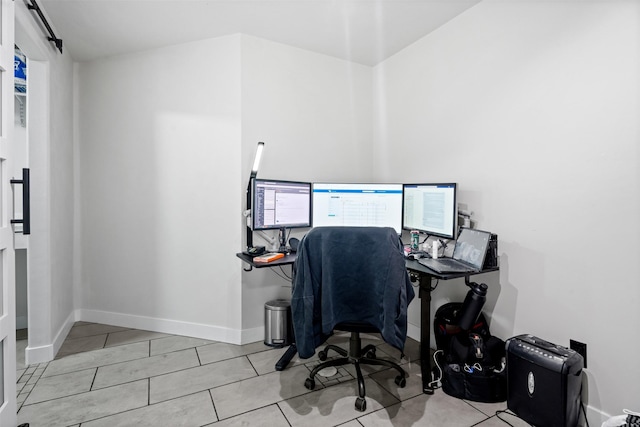 tiled office space featuring a barn door and baseboards