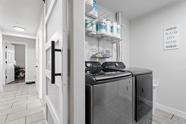 washroom featuring baseboards, laundry area, and washing machine and clothes dryer