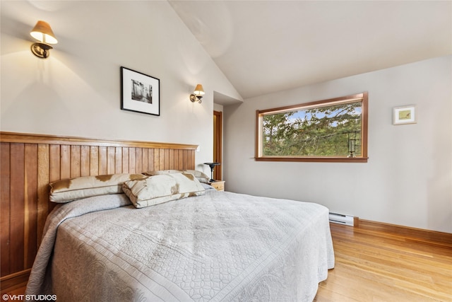 bedroom featuring wood finished floors, lofted ceiling, and a baseboard radiator