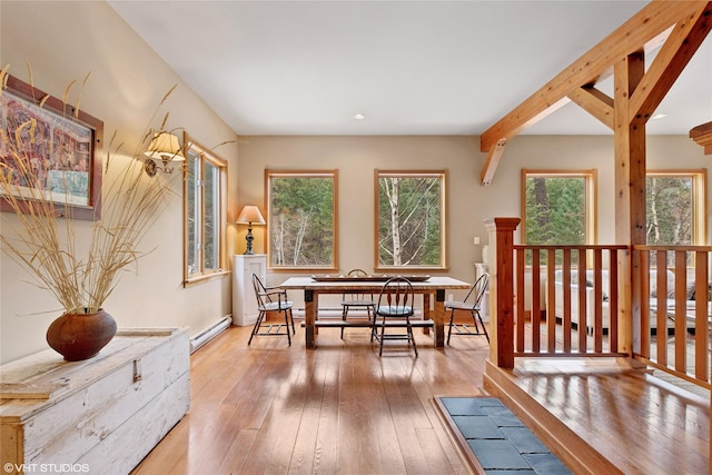 dining area with a baseboard heating unit, beamed ceiling, and hardwood / wood-style flooring