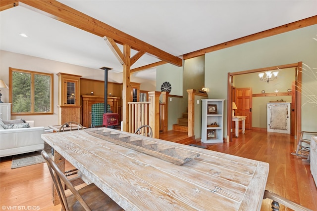 dining room with beamed ceiling, wood-type flooring, a wood stove, and stairs