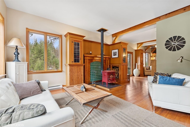 living room with a baseboard heating unit, wood-type flooring, beam ceiling, and a wood stove