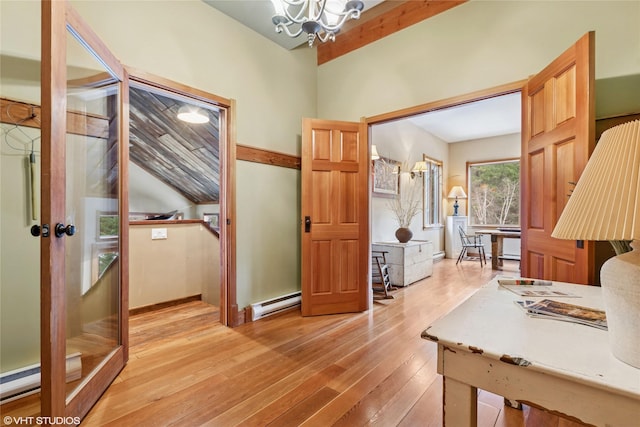 interior space featuring a baseboard heating unit, baseboards, a chandelier, and light wood finished floors