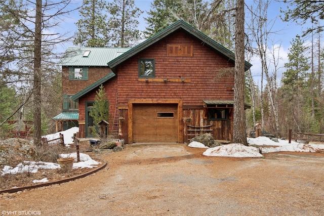 view of front of property with an attached garage, metal roof, and driveway