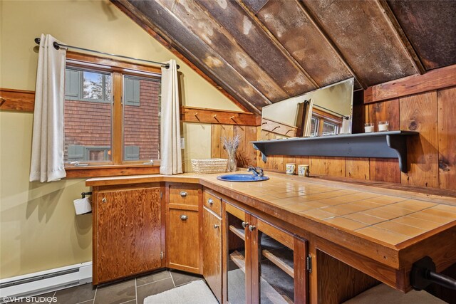 588 Ranch Rd, Bigfork, MT 59911 - kitchen featuring vaulted ceiling, a baseboard heating unit, brown cabinets, tile patterned flooring, and tile counters