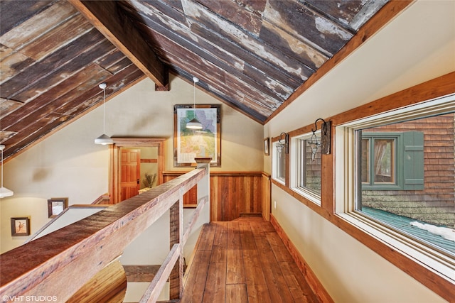 hallway featuring hardwood / wood-style floors, a wainscoted wall, lofted ceiling, wood walls, and an upstairs landing