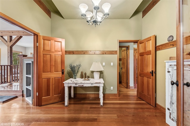 corridor with wood finished floors, baseboards, and a chandelier