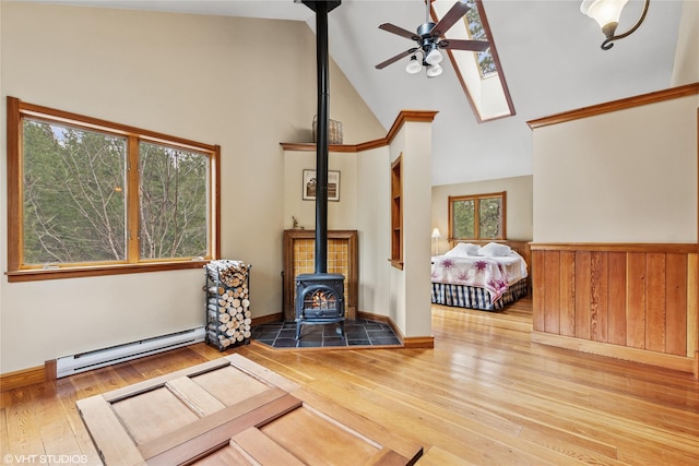 588 Ranch Rd, Bigfork, MT 59911 - living room with a baseboard heating unit, a wood stove, ceiling fan, hardwood / wood-style flooring, and high vaulted ceiling