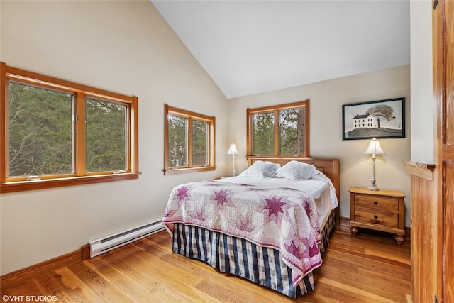 bedroom with vaulted ceiling, wood finished floors, baseboards, and a baseboard radiator