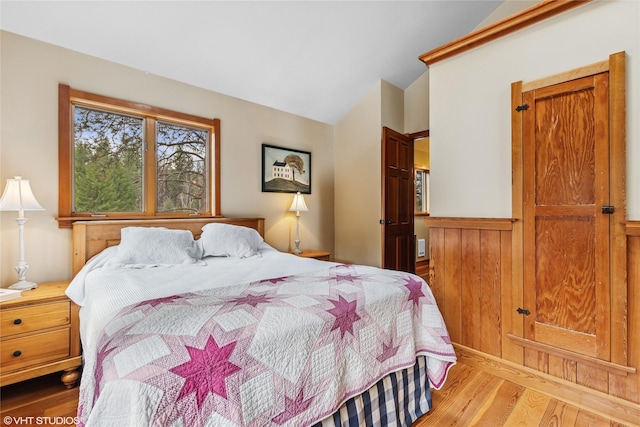 588 Ranch Rd, Bigfork, MT 59911 - bedroom featuring wood finished floors, vaulted ceiling, and wainscoting