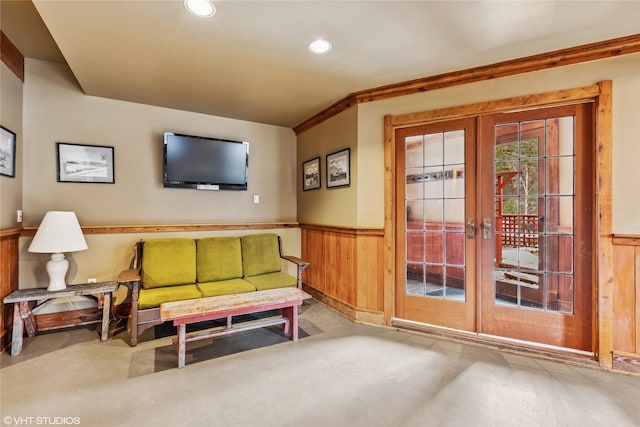 living area featuring wooden walls, finished concrete flooring, recessed lighting, french doors, and wainscoting