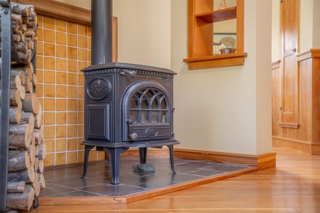 interior details with baseboards, wood finished floors, and a wood stove