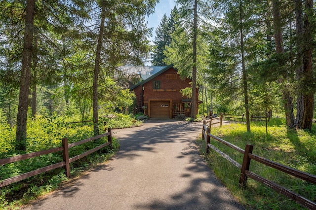 view of front of house featuring an attached garage, driveway, and fence