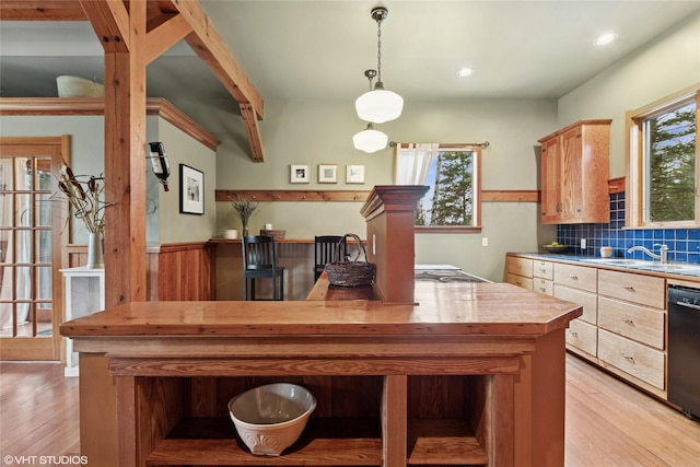 kitchen featuring backsplash, black dishwasher, light wood finished floors, and a sink