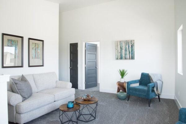 carpeted living room featuring a high ceiling and baseboards