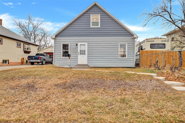 rear view of property featuring entry steps, a yard, and fence