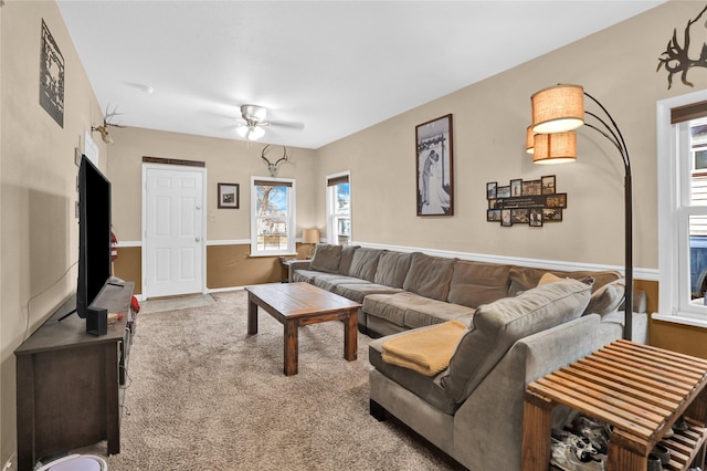 carpeted living area with baseboards and a ceiling fan