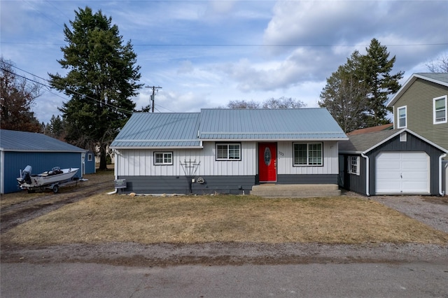 view of front of house with a garage, board and batten siding, metal roof, and aphalt driveway