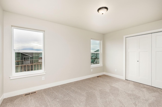 unfurnished bedroom featuring visible vents, baseboards, carpet, and a closet