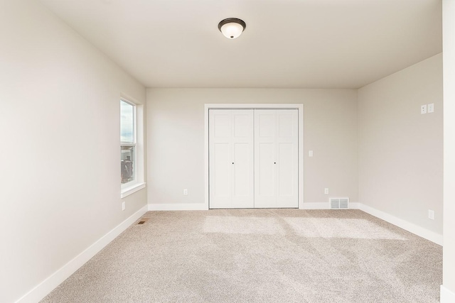 unfurnished bedroom featuring visible vents, baseboards, a closet, and carpet flooring