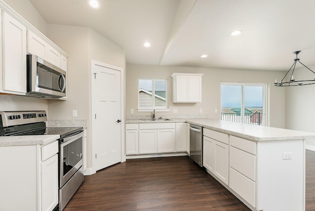 kitchen with a sink, a peninsula, dark wood-style floors, and stainless steel appliances