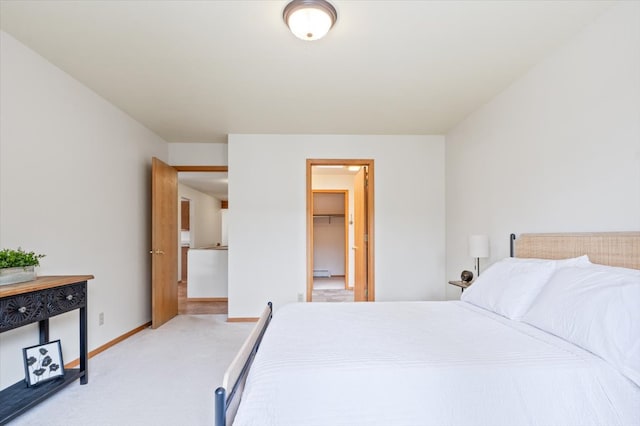 bedroom featuring baseboard heating, a walk in closet, baseboards, and carpet floors