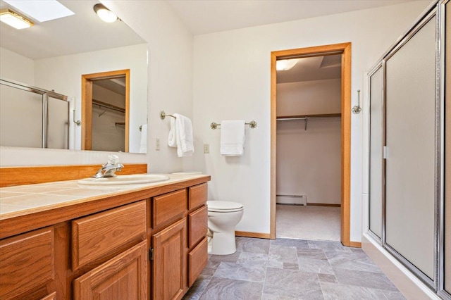 bathroom featuring a shower stall, a baseboard heating unit, toilet, a skylight, and vanity