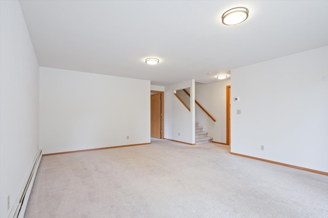 empty room featuring a baseboard radiator, light carpet, baseboards, and stairway