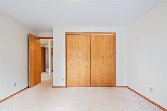 unfurnished bedroom featuring a closet, light colored carpet, and baseboards