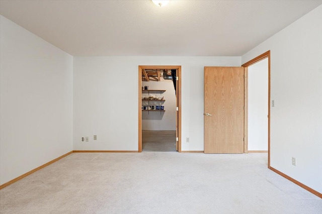 unfurnished bedroom featuring a walk in closet, carpet floors, and baseboards