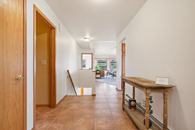 corridor featuring an upstairs landing, light tile patterned floors, and baseboards