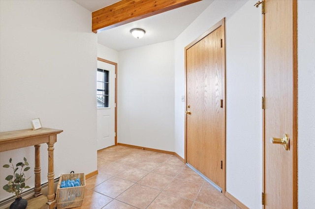 interior space featuring light tile patterned flooring, beamed ceiling, and baseboards