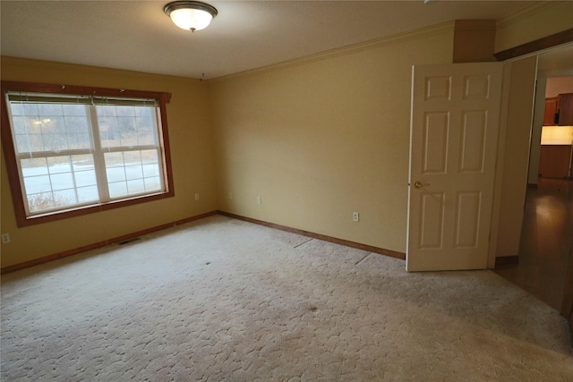 spare room featuring visible vents, baseboards, carpet, and crown molding