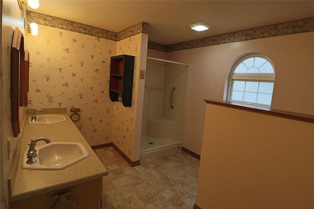 full bath with wallpapered walls, walk in shower, baseboards, and a sink