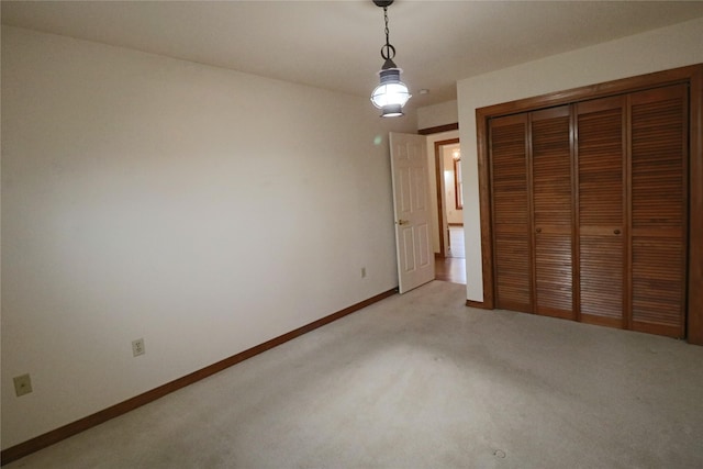 unfurnished bedroom with a closet, light colored carpet, and baseboards